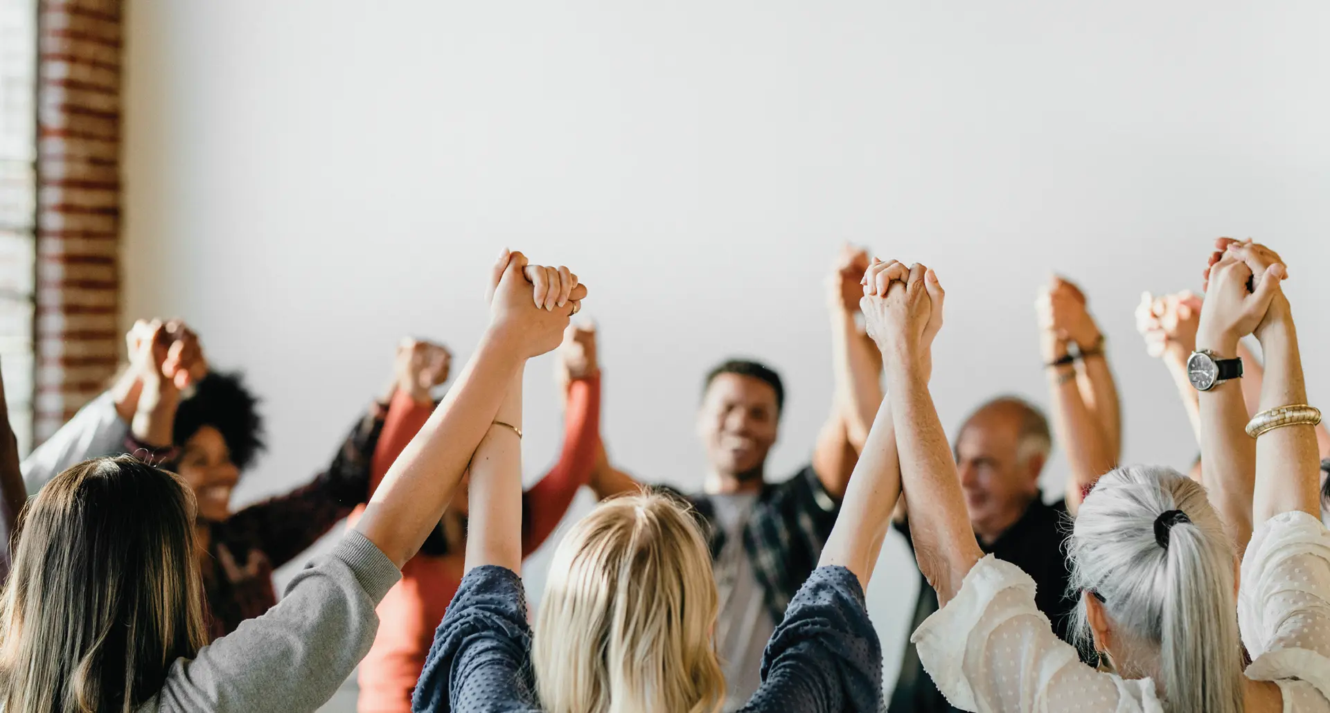 A diverse group of people standing in a circle, holding hands with their arms raised high in a gesture of unity and solidarity. A red graphic overlay on the left reads 'FROM AWARENESS TO ACTION' followed by the hashtag '#MENTALHEALTHMATTERS'.